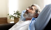 Mature man relaxing at home sitting on the sofa with hands behind the head feeling satisfaction. Copy space Mature man relaxing at home sitting on the sofa with hands behind the head feeling satisfaction. Copy space. Lifestyle concept.